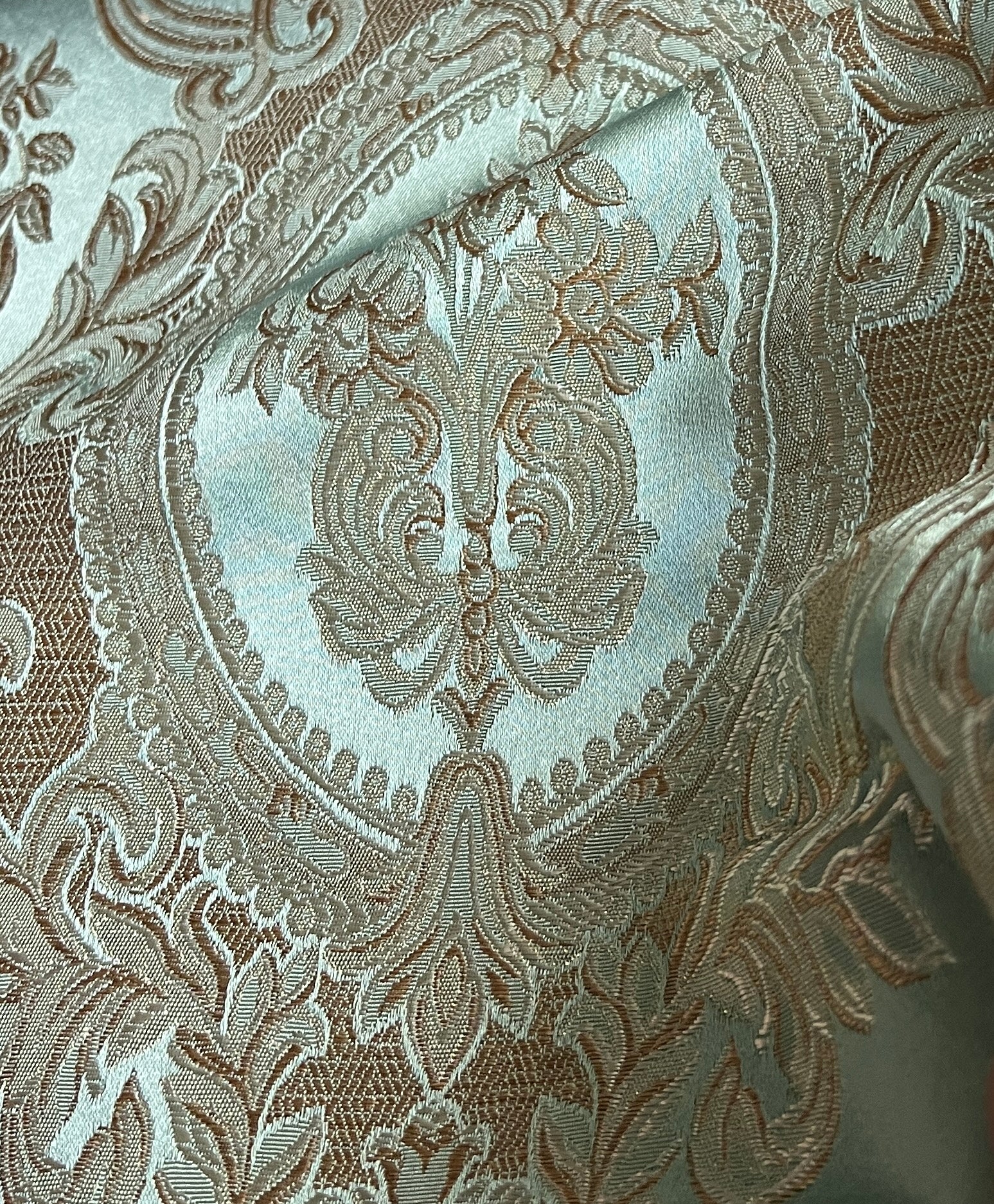 Close-up of damask ornate floral pattern on fabric with Pista color background