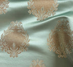 Decorative fabric pattern with intricate white designs on a Pista background