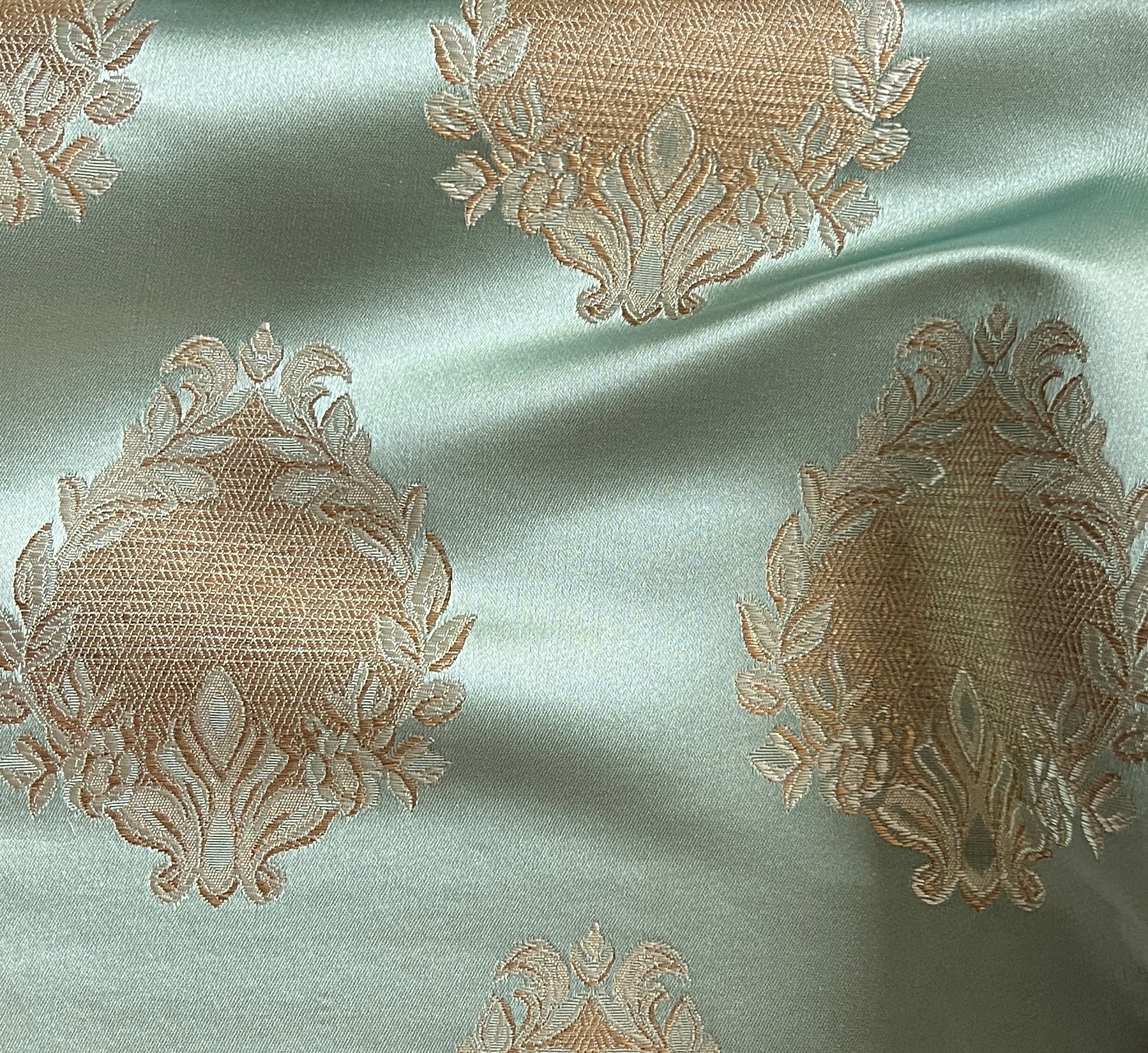 Decorative fabric pattern with intricate white designs on a Pista background