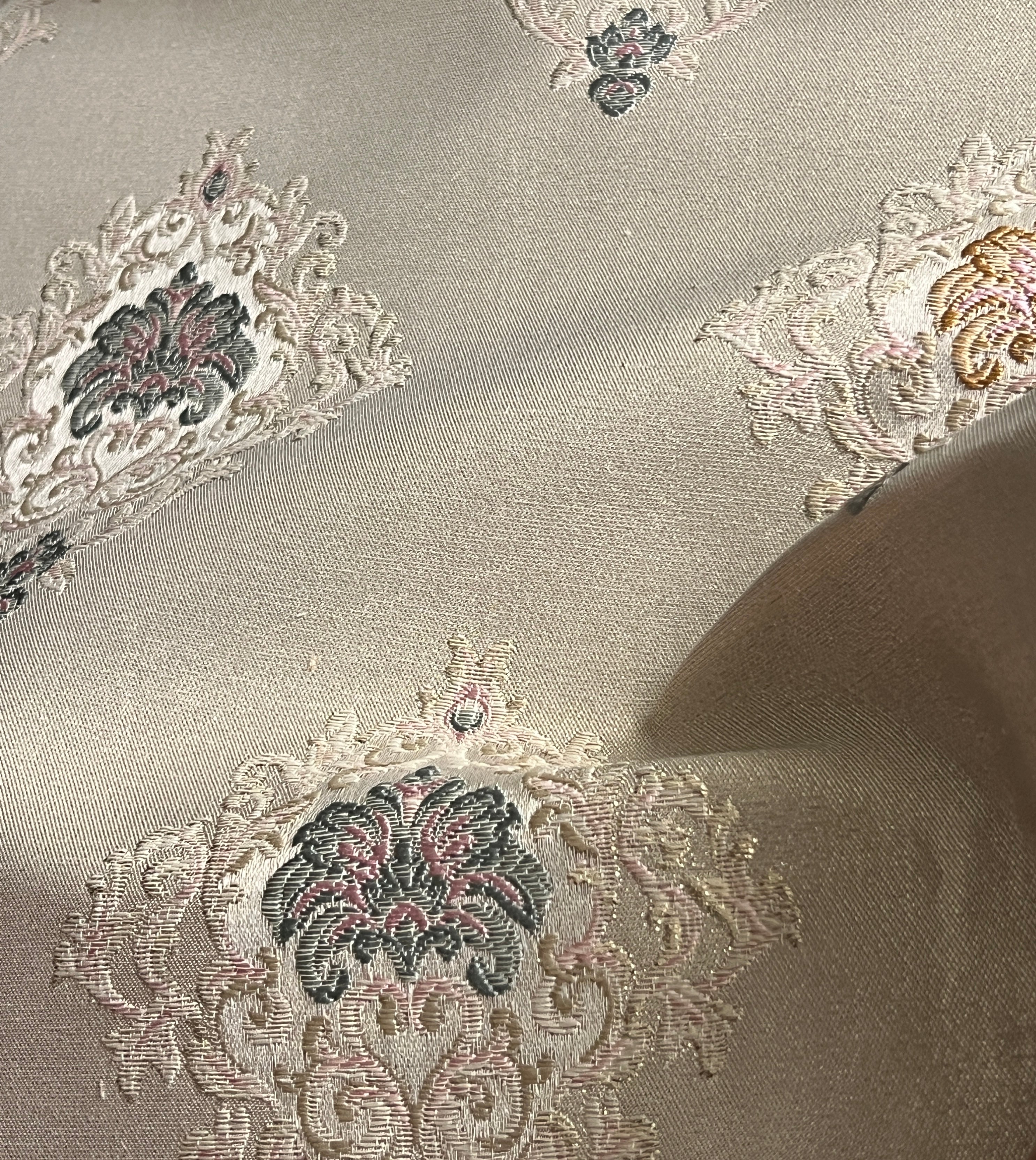 Decorative fabric with intricate patterns on a Pinkish background