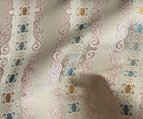 Decorative fabric pattern with intricate designs and color accents on a Pinkish background