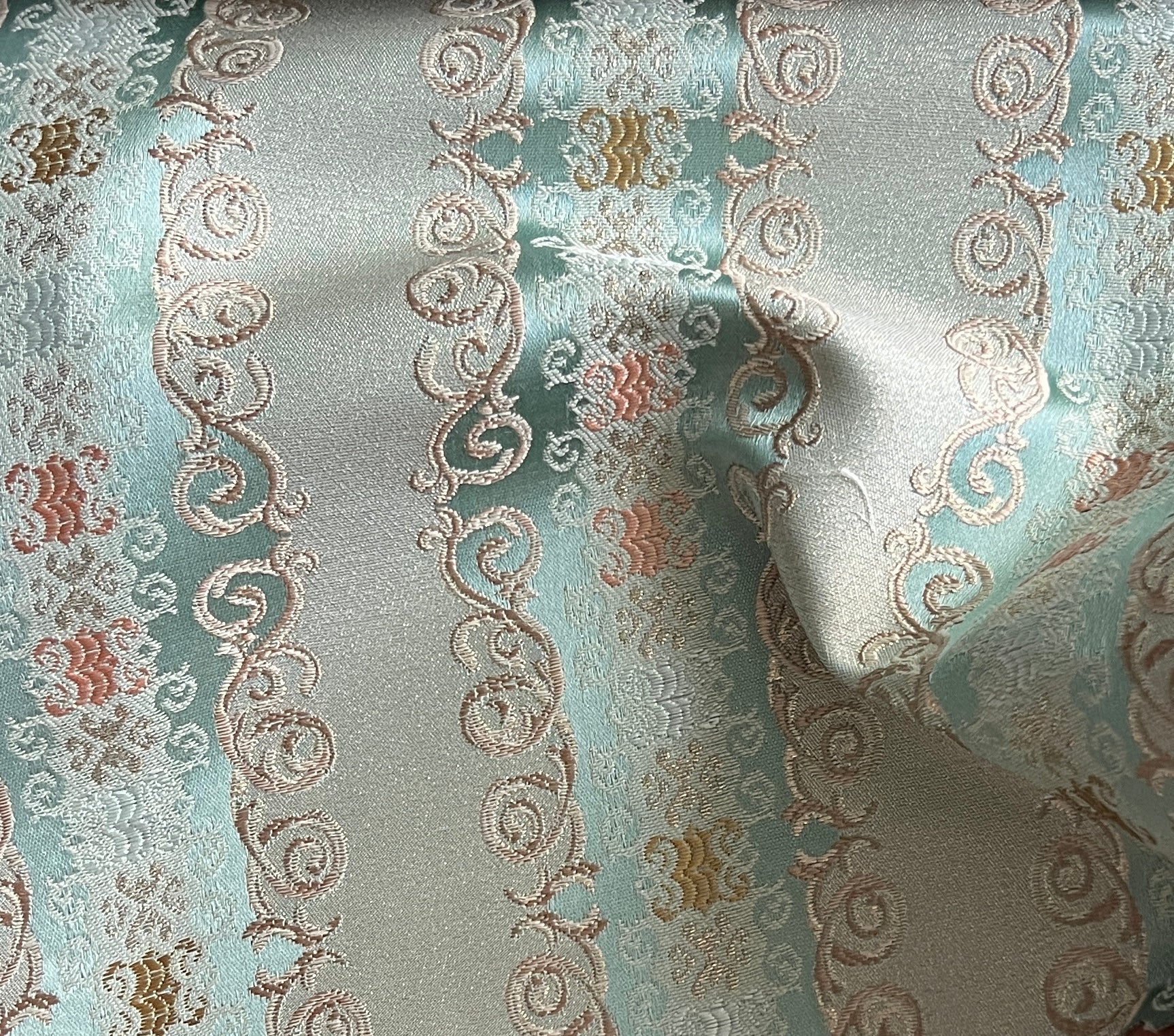 Decorative fabric pattern with intricate designs and color accents on a Pista background