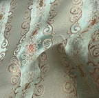Decorative fabric pattern with intricate designs and color accents on a Pista background