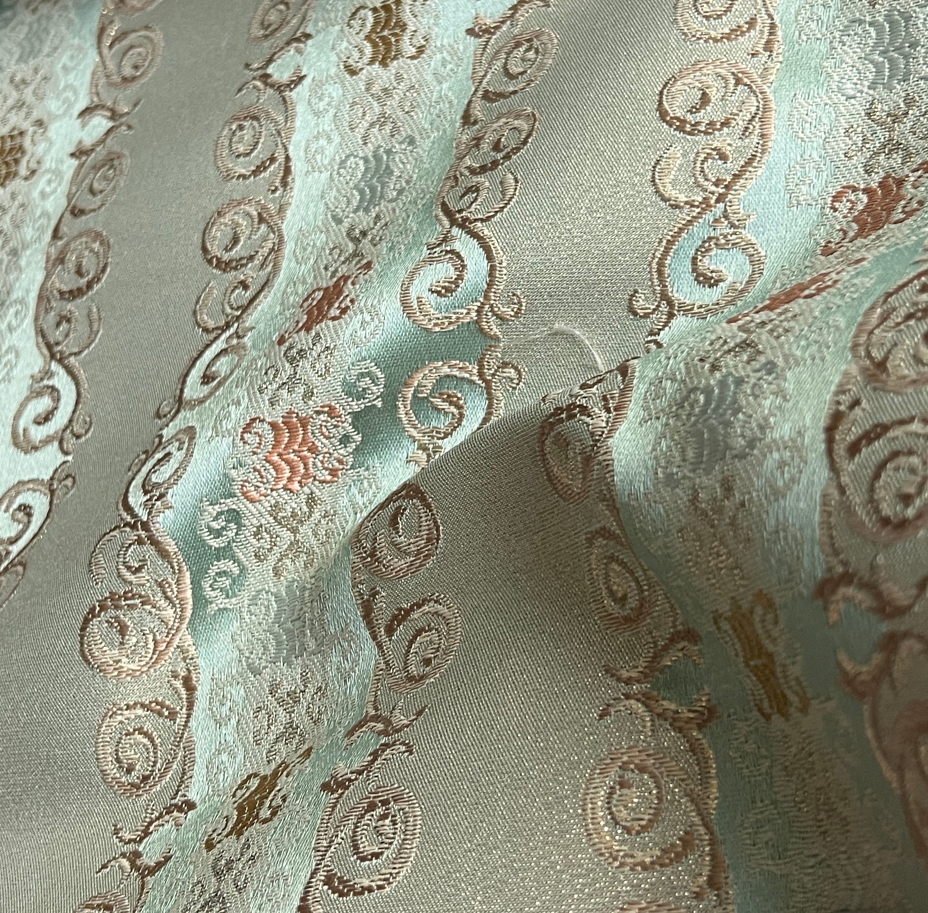 Decorative fabric pattern with intricate designs and color accents on a Pista background