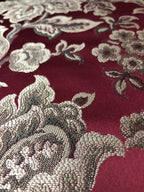 Maroon floral jacquard fabric folded, texture close-up.