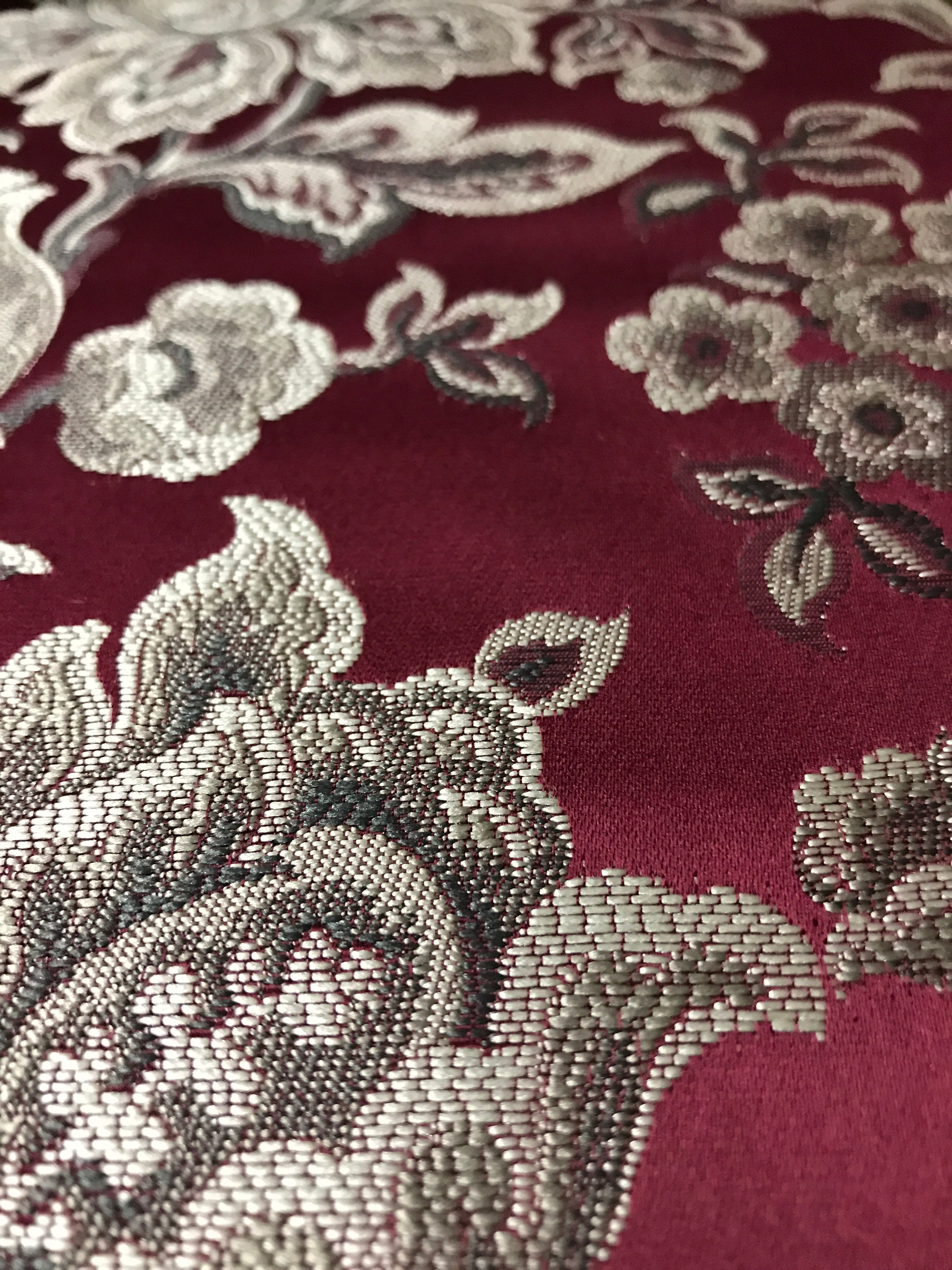 Maroon floral jacquard fabric folded, texture close-up.