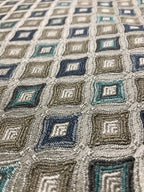 Close-up of a textured fabric with geometric pattern in shades of blue, gray, and beige. Teal Sage