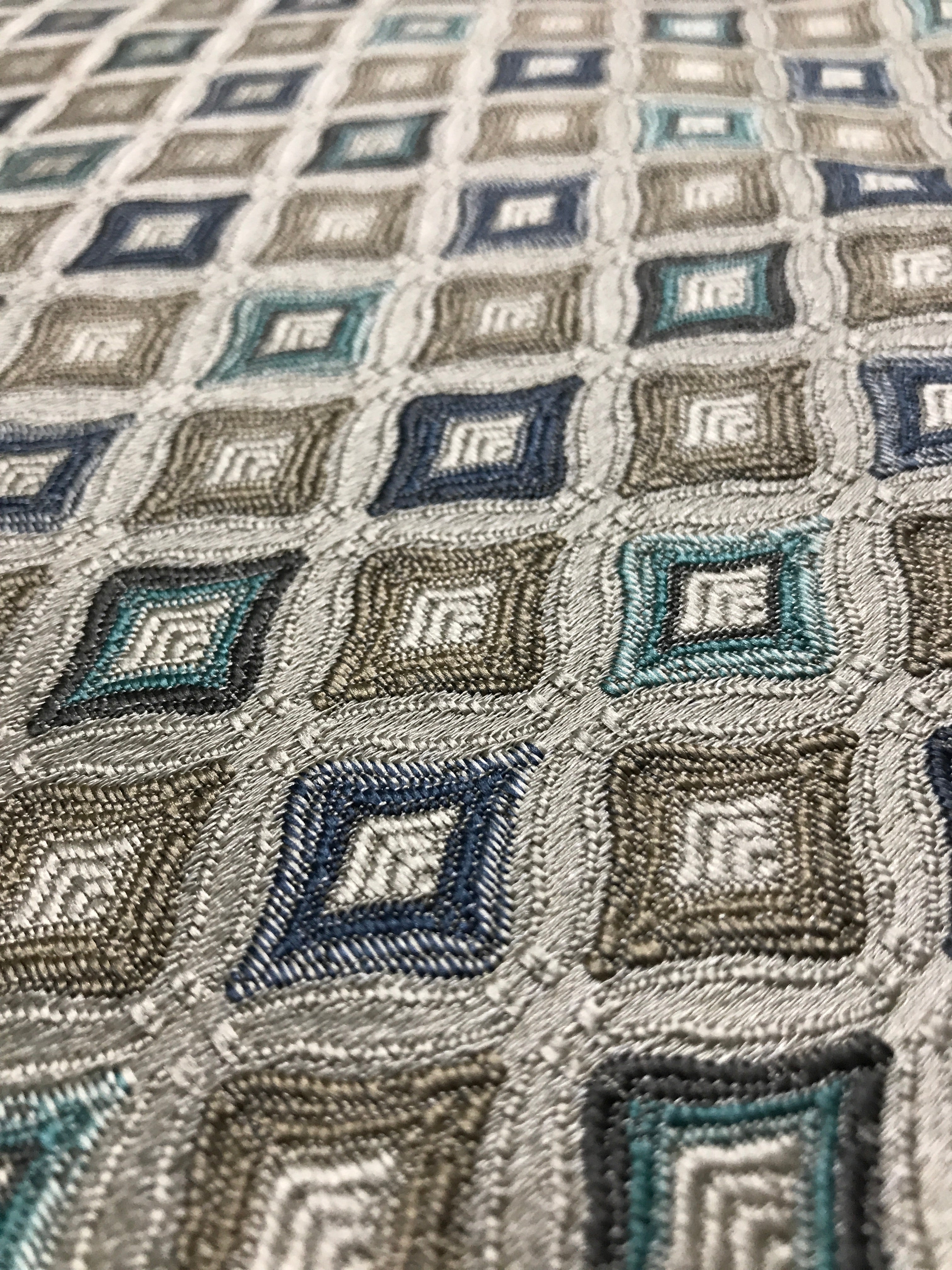 Close-up of a textured fabric with geometric pattern in shades of blue, gray, and beige. Teal Sage