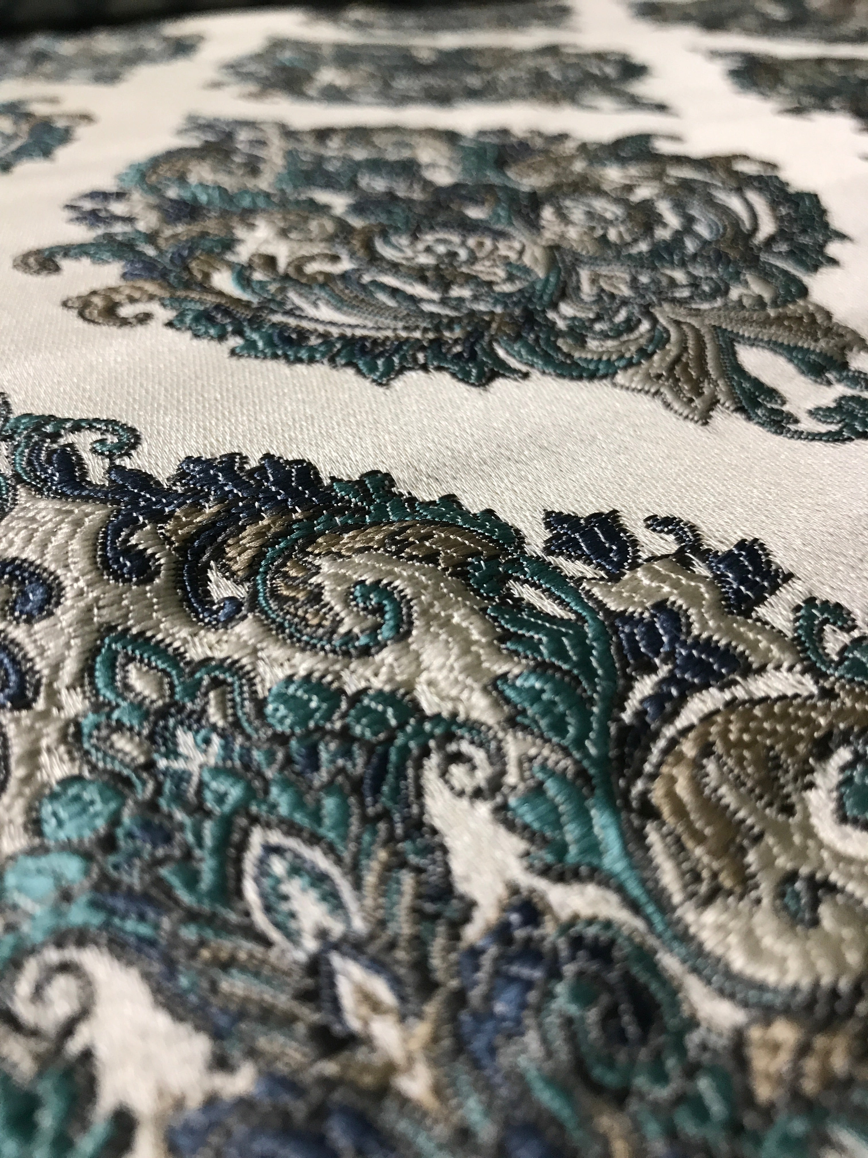 Close-up of intricate paisley pattern fabric with teal and brown colors. Teal Sage
