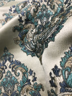 Close-up of intricate paisley pattern fabric with blue and gold details on a white background Teal Sage