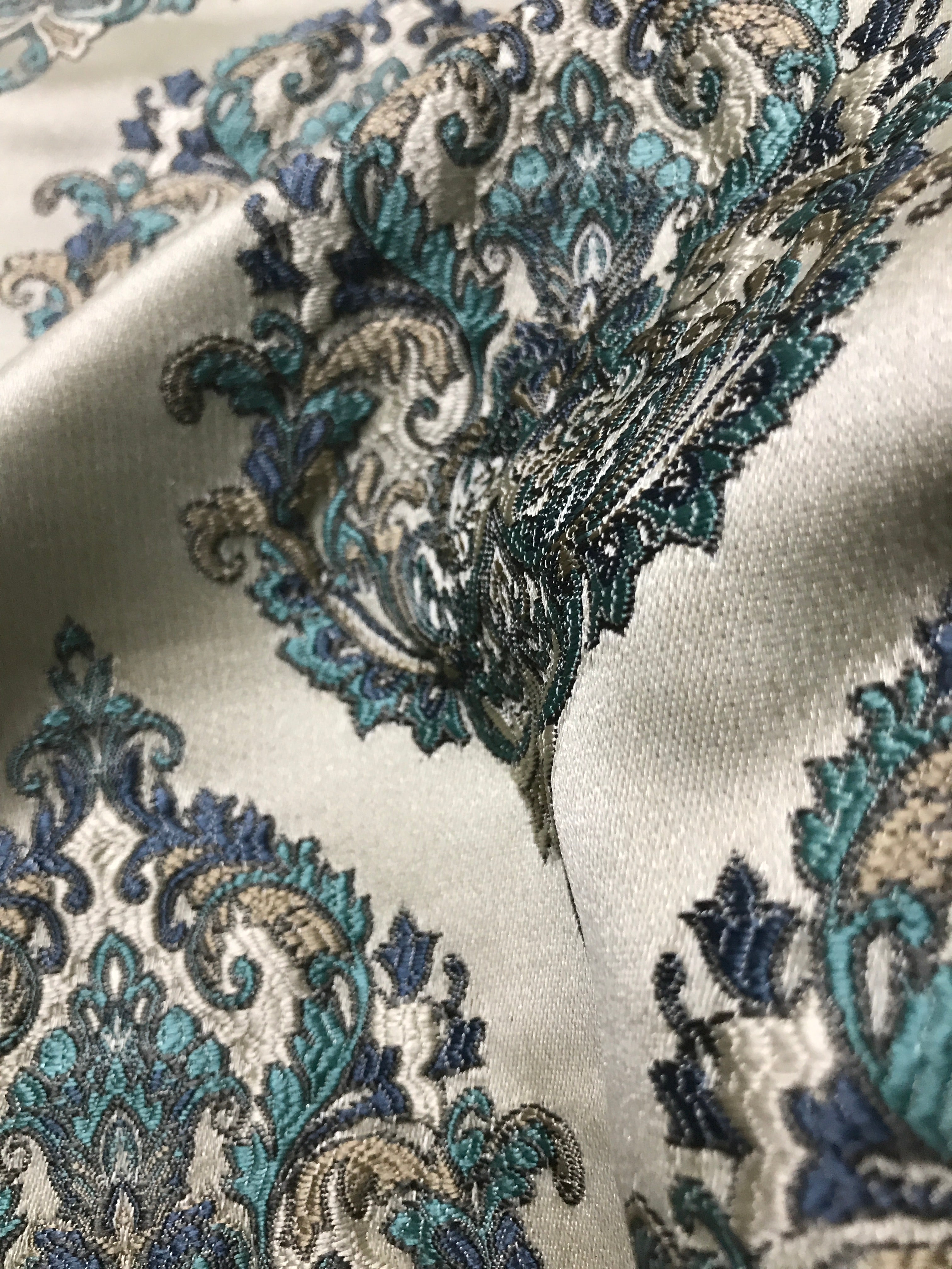 Close-up of intricate paisley pattern fabric with blue and gold details on a white background Teal Sage