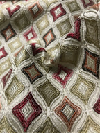 Close-up of patterned fabric with geometric design in red, beige, and brown. Sage Rose