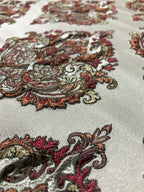 Close-up of intricate paisley pattern on fabric with red, brown, and beige colors. Sage Rose
