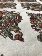 Close-up of embroidered fabric with intricate patterns on a white background  Sage Rose