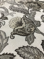 Close-up of decorative fabric with intricate Stone Age floral pattern on a beige background