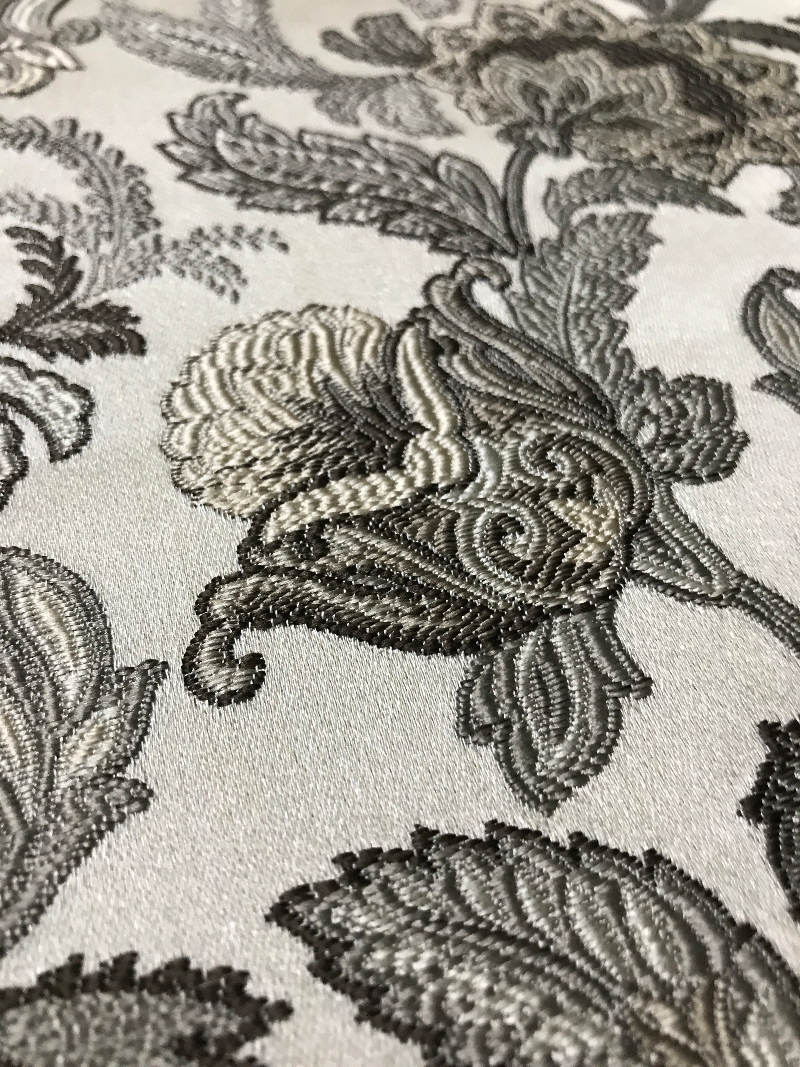 Close-up of decorative fabric with intricate Stone Age floral pattern on a beige background