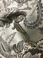 Close-up of intricate Stone Age lace fabric with floral patterns on a white background