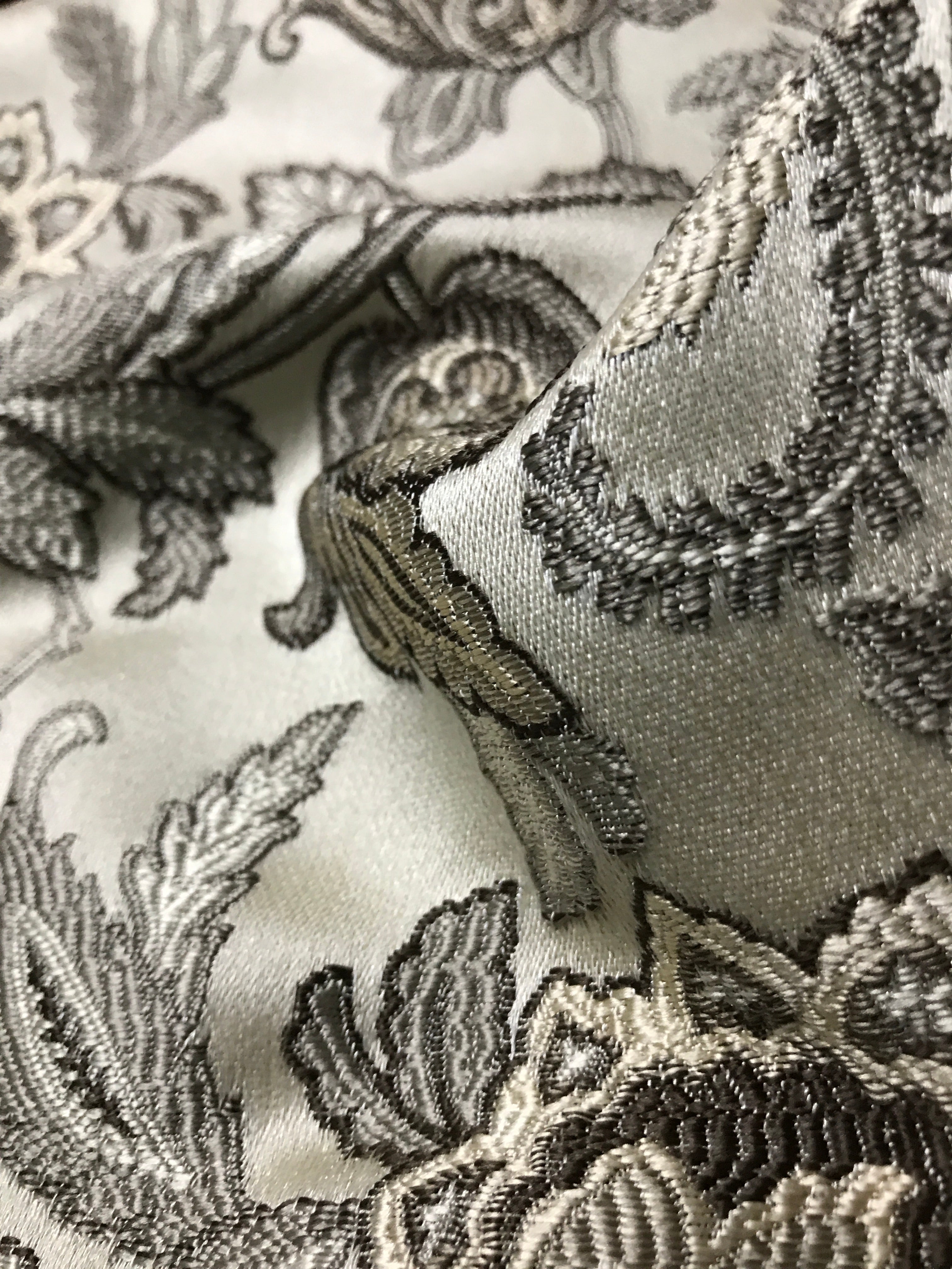 Close-up of intricate Stone Age lace fabric with floral patterns on a white background