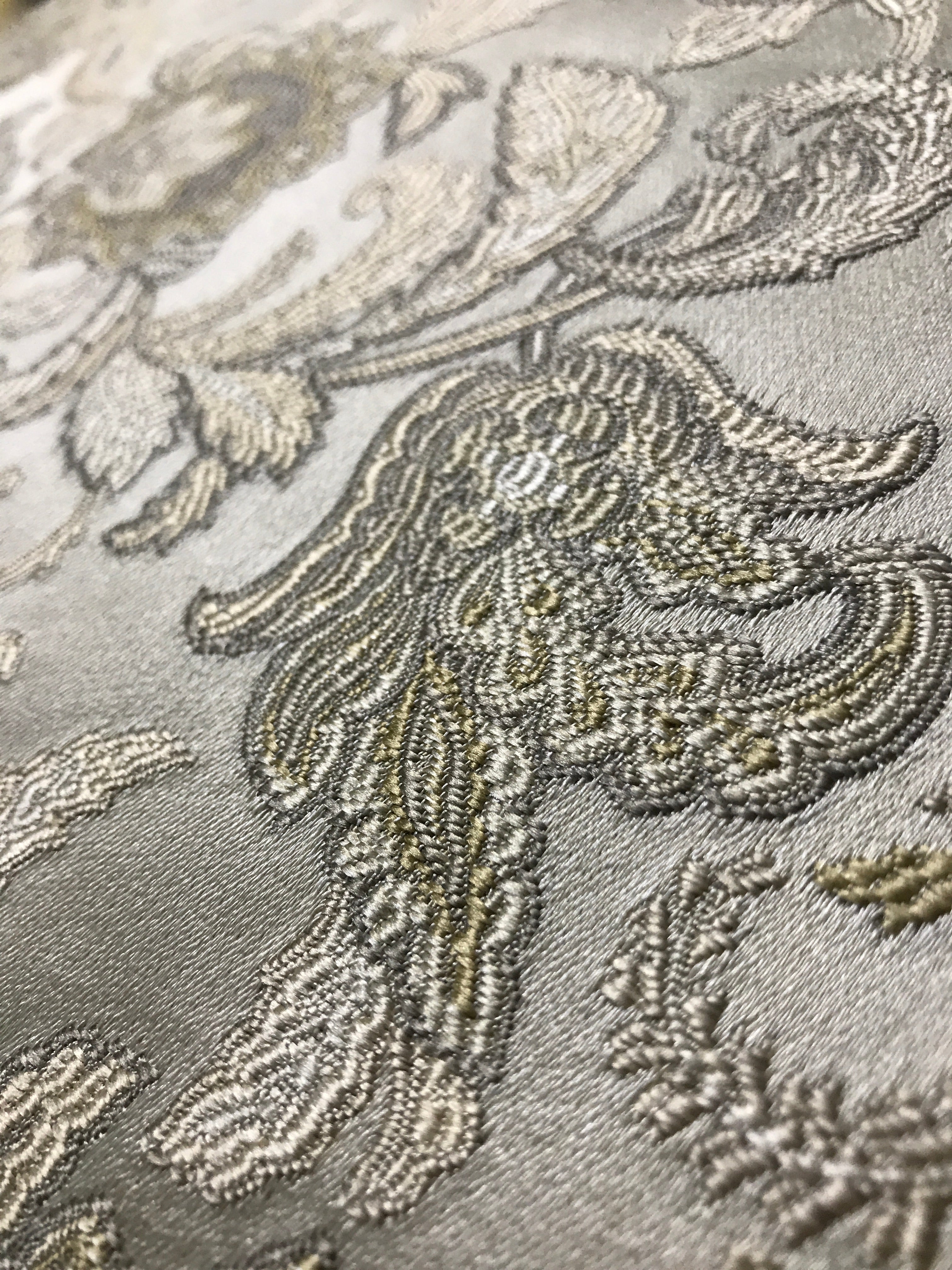 Close-up of embroidered fabric with floral patterns on a gray background Olive Sage