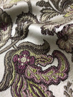Close-up of embroidered fabric with floral patterns in purple and green on a white background Heritage Sage