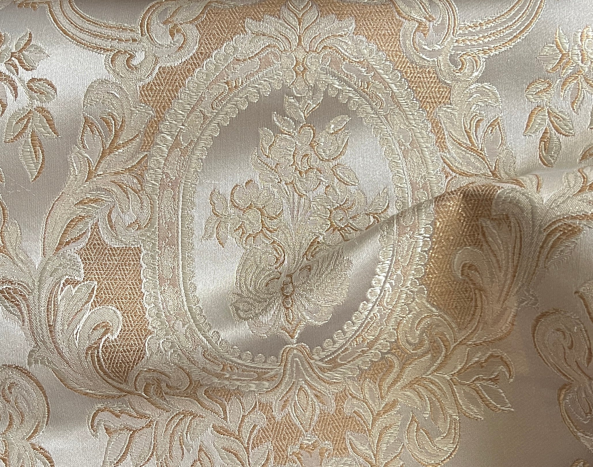 Close-up of damask ornate floral pattern on fabric with Beige color background