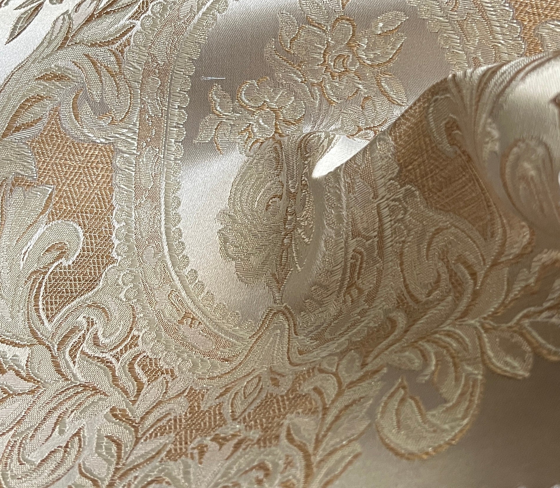 Close-up of damask ornate floral pattern on fabric with Beige color background