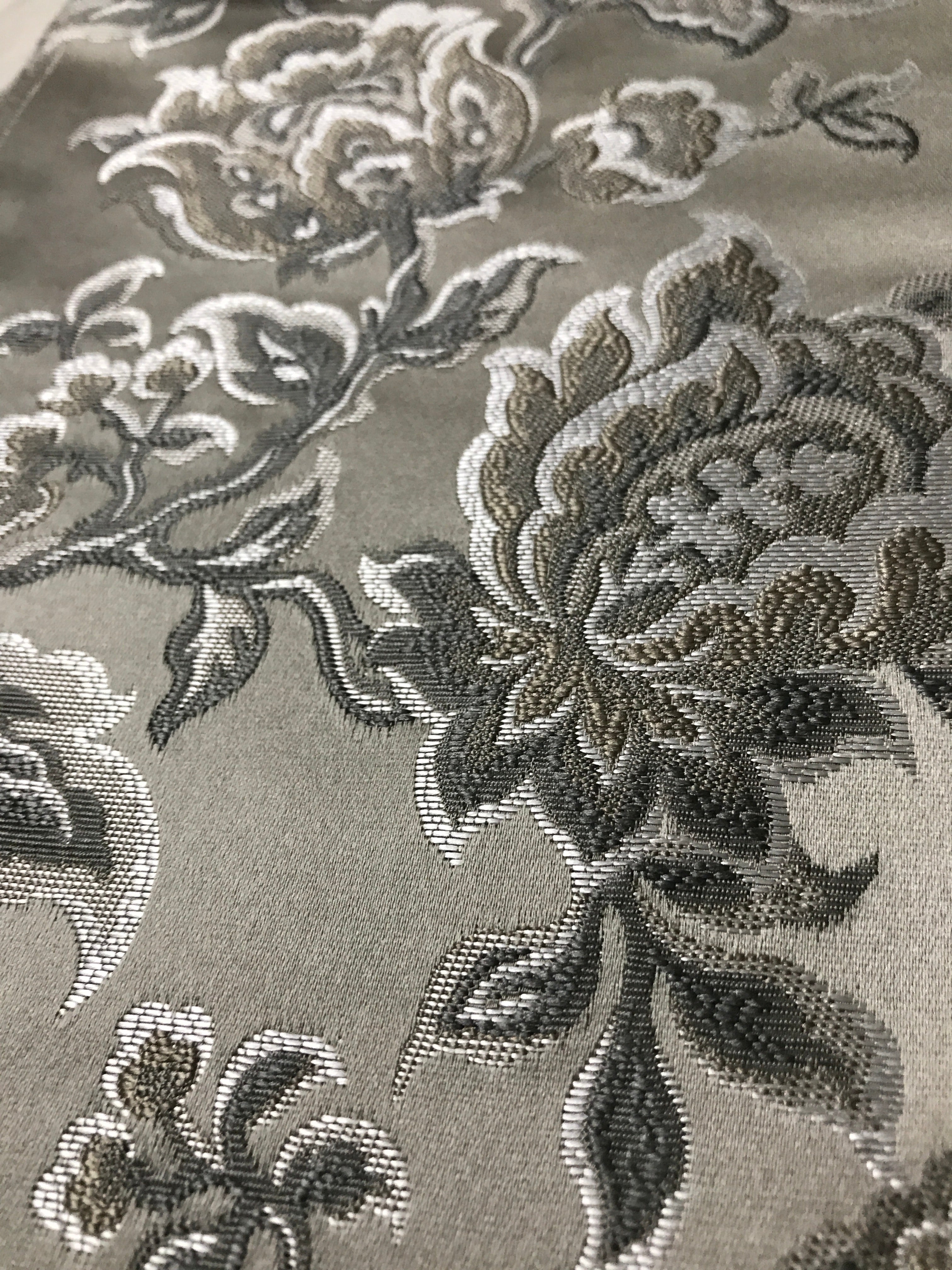 Silver floral jacquard fabric folded, texture close-up.