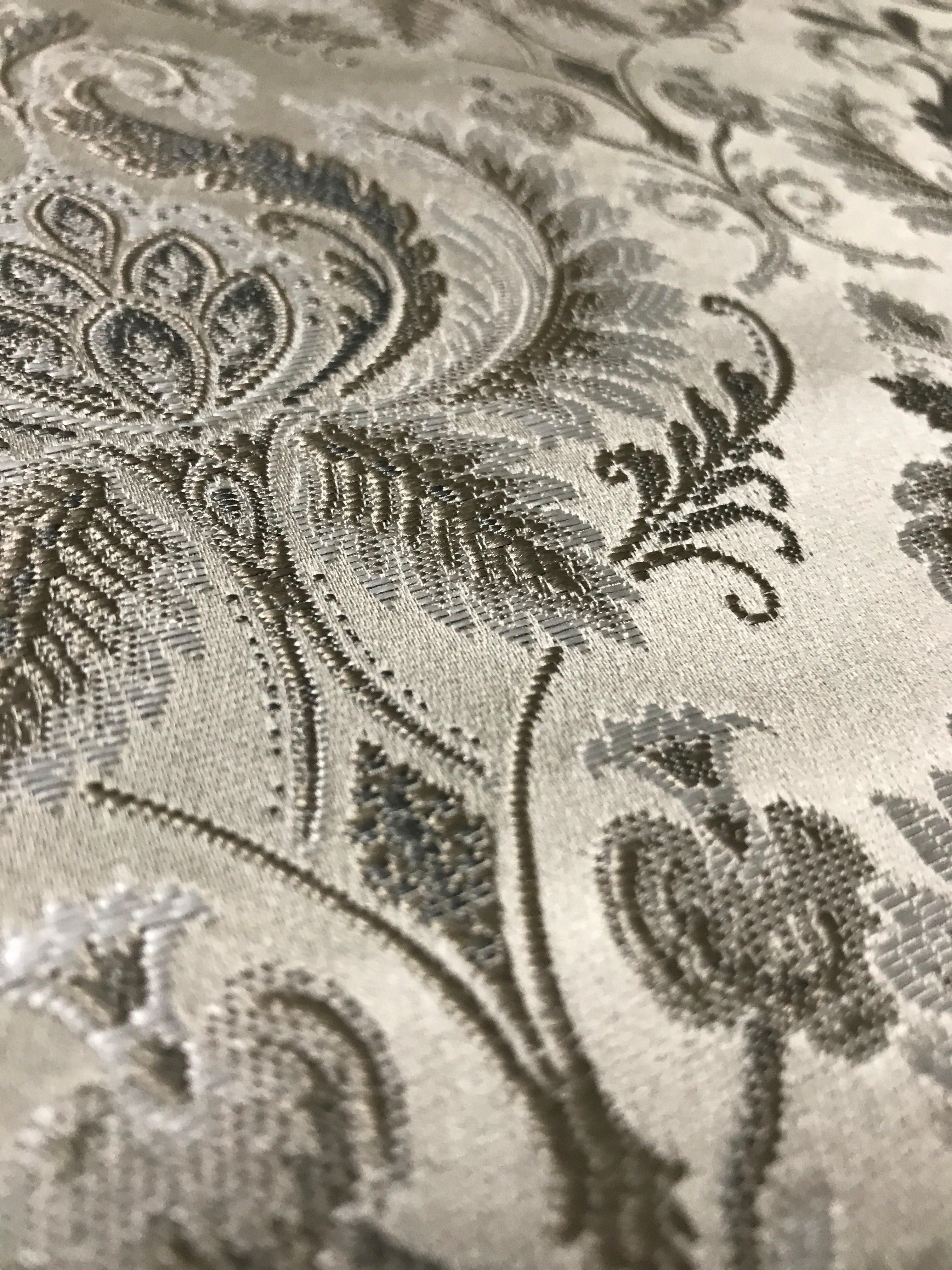 Silver damask fabric folded, texture and sheen close-up